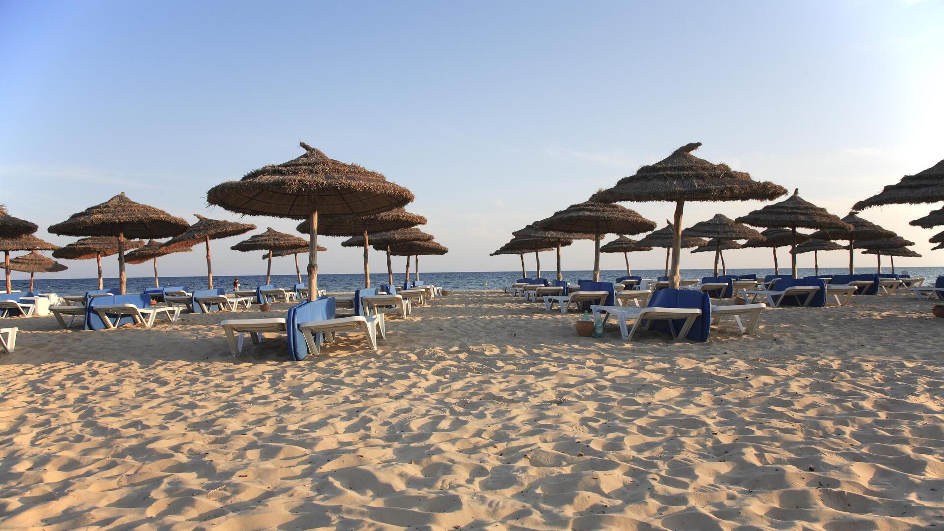 Лежаки и соломенные зонтики на пляже, Хаммамет, Тунис.